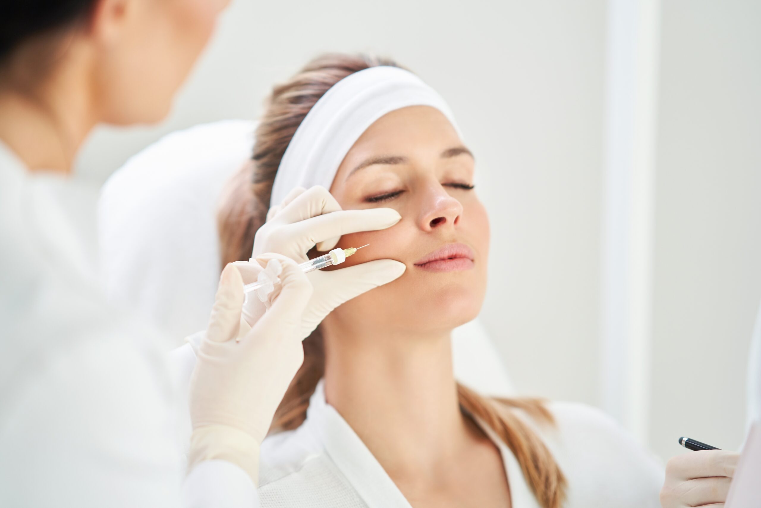 Young woman getting a Daxxify injection in her face by a esthetician.